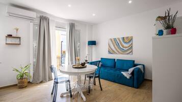 Un salon moderne avec un canapé bleu, une table à manger avec des chaises et un tableau accroché au mur.