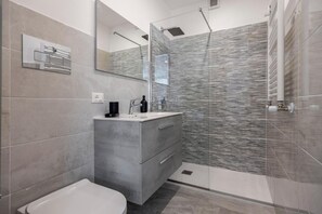 Ein modernes Badezimmer mit Toilette, Waschtisch und Duschbereich.