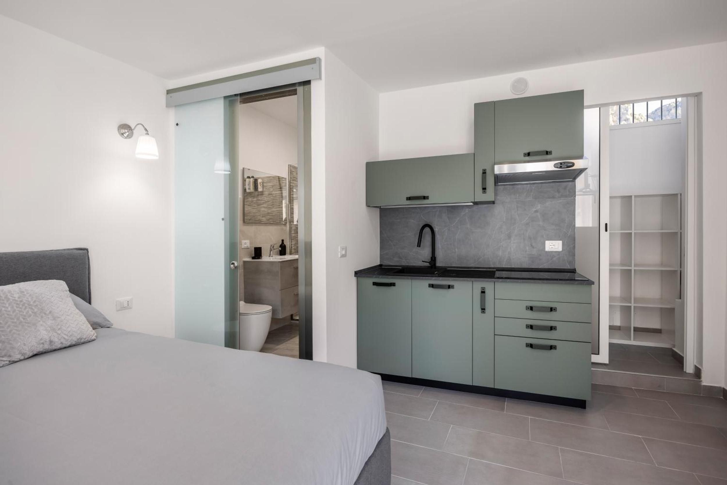 Une chambre compacte comprenant un lit, une kitchenette et une salle de bain.