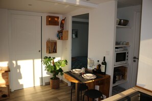 A compact kitchen with a dining table, chairs, a potted plant, and a microwave. - A lovely, bright one-bedroom apartment in a quiet location with a view of the garden. Perfect for a vacation. (Macau)