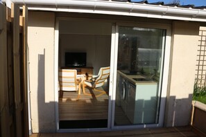 A room with a sliding glass door leading to a balcony, a television, a small kitchen area, and a seating area with chairs. - A lovely, bright one-bedroom apartment in a quiet location with a view of the garden. Perfect for a vacation. (Macau)
