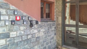 A stone wall with various security devices, a window, and a door with glass panels. - GRAN PARADIS (San Pietro)