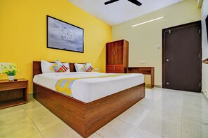 A bedroom with a bed, a nightstand, a wooden wardrobe, a door, and a wall-mounted artwork. - Hotel O Saiinn (Paud)