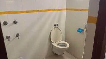 A small, clean bathroom with a toilet, a hand dryer, and a trash bin.