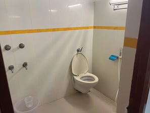 Et lille, rent badeværelse med toilet, håndtørrer og skraldespand.