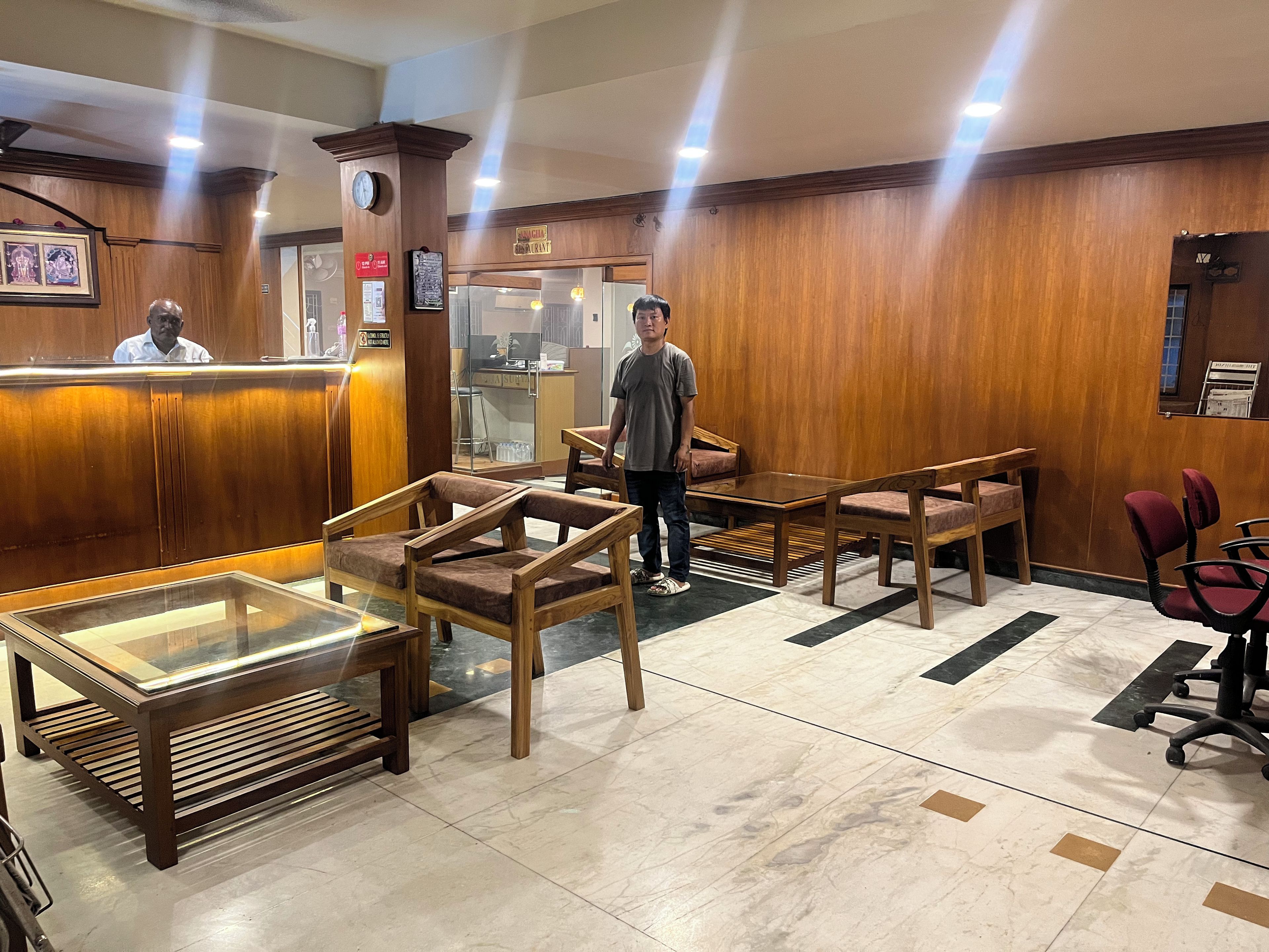 Un área de recepción con muebles de madera, una vitrina de vidrio y un reloj en la pared.