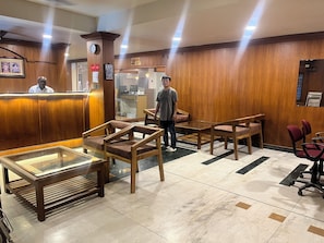 A reception area with wooden furniture, a glass display case, and a clock on the wall.