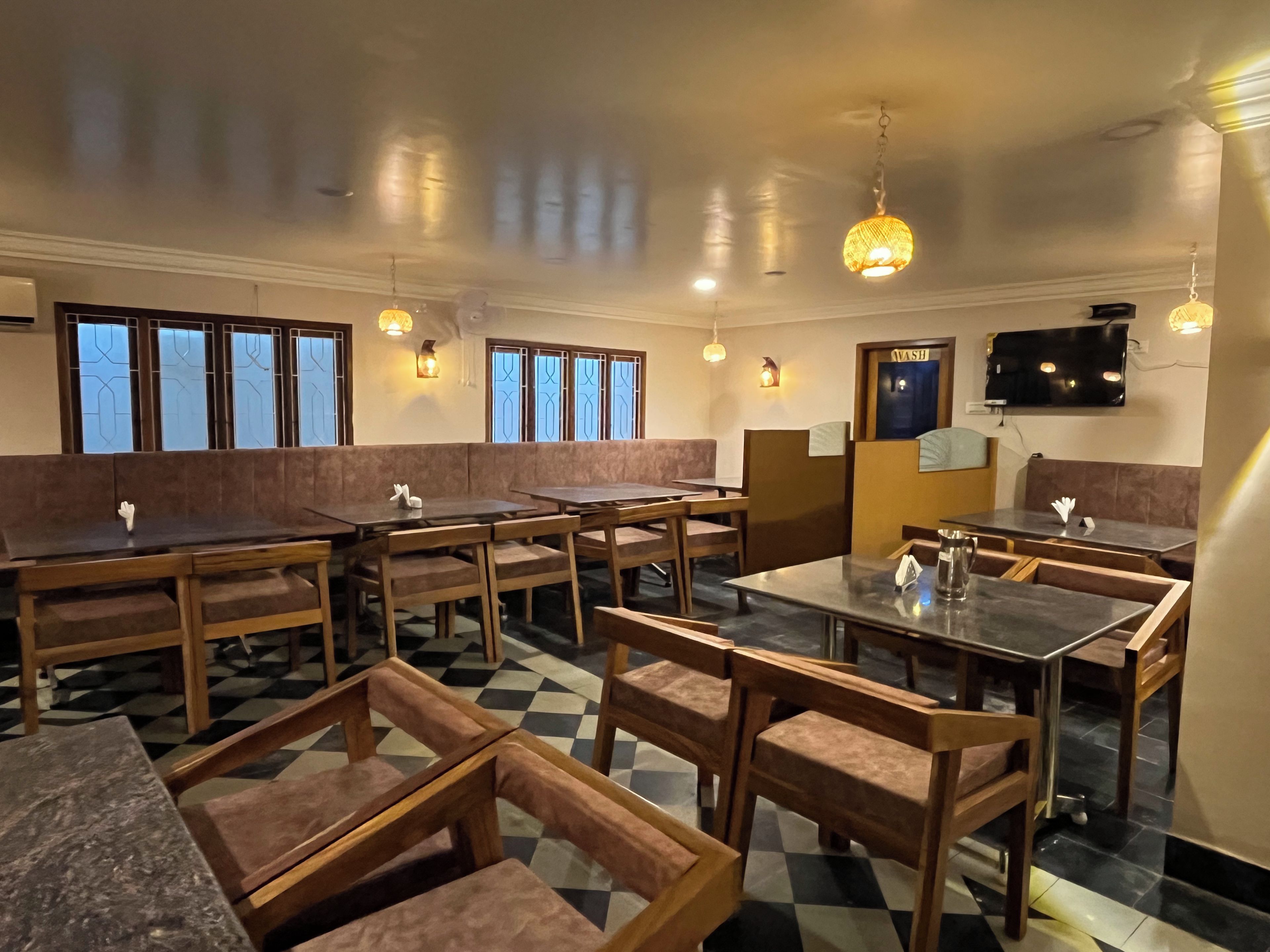 Interior de restaurant amb seients separats per cabines, taules i una recepció.