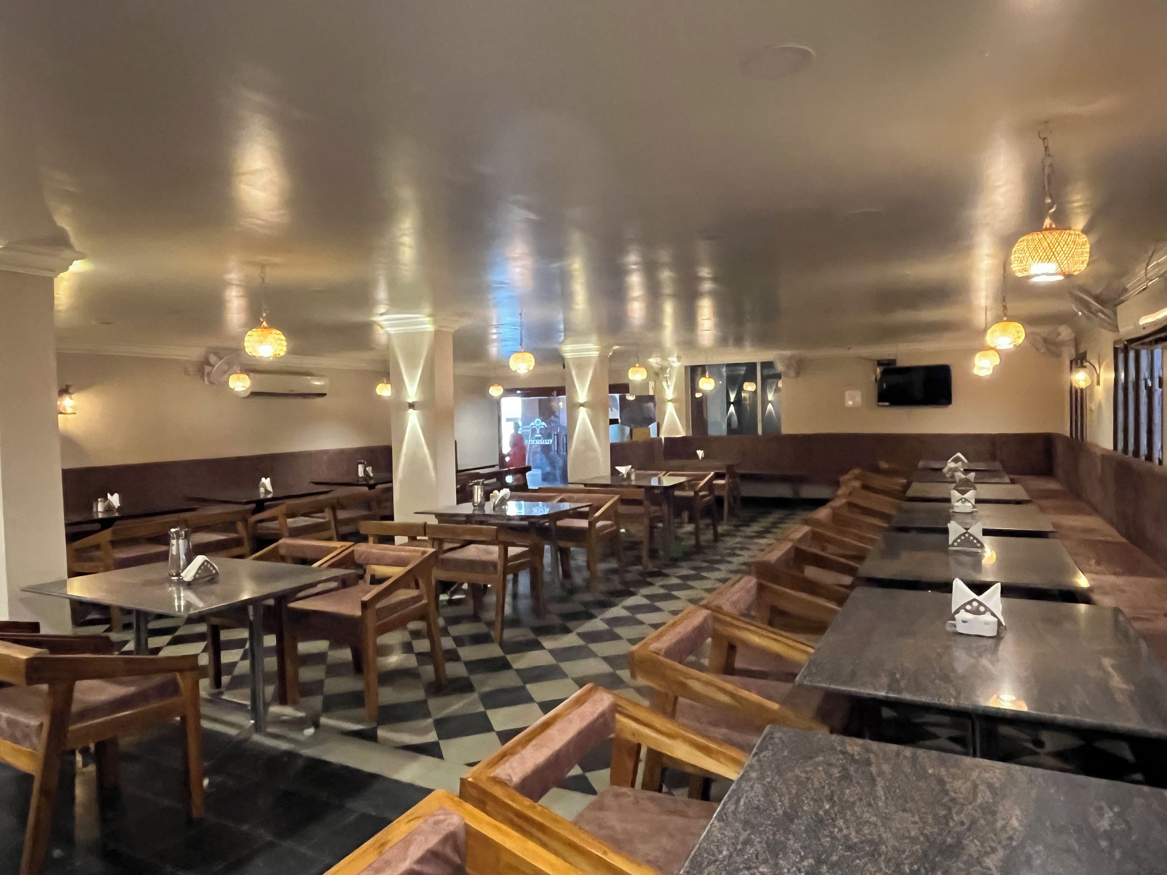 A restaurant interior with booths, tables, and hanging pendant lights.