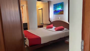 Habitación de hotel con cama, escritorio, silla, espejo y un cuadro en la pared.