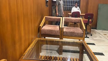 Una habitación con paredes de madera, una mesa con superficie de vidrio y dos sillas.