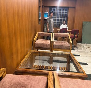 A room with wooden walls, a glass-top table, and two chairs.