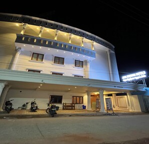 A hotel with a white facade, multiple windows, and a signboard.