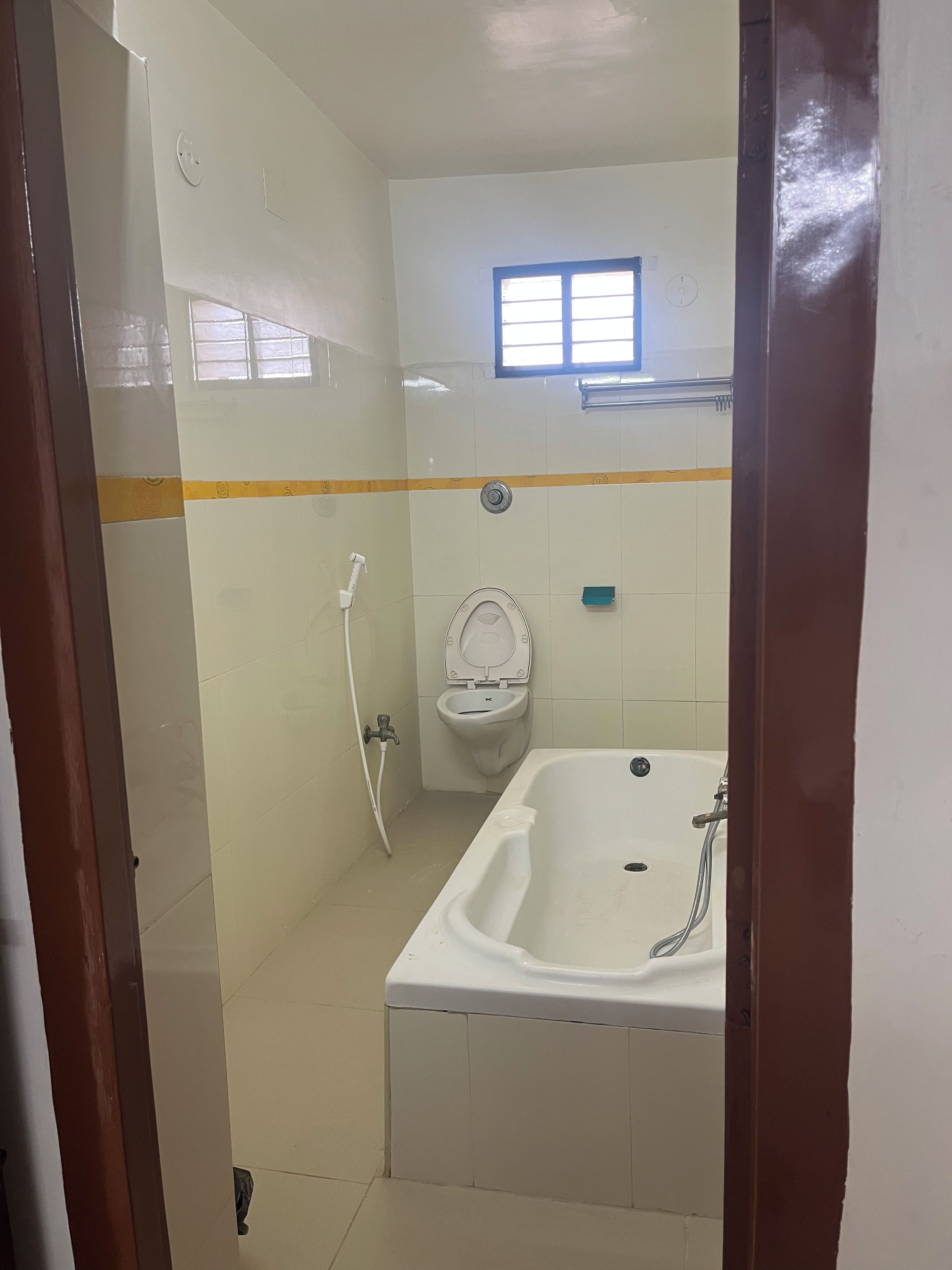 A bathroom with a bathtub, toilet, and a window.