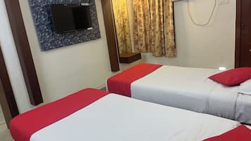 Habitación de hotel con dos camas, un televisor de pantalla plana en la pared, una ventana con cortinas e un equipo de aire acondicionado.