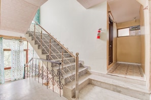 A staircase with a handrail and a fire extinguisher mounted on the wall. - Collection O Airport Road Solina (Srinagar)