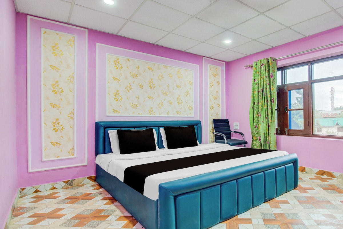 A bedroom with a bed, a chair, a window with curtains, and patterned walls.