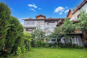 A two-story building with a symmetrical facade, multiple windows, and satellite dishes. - Collection O Airport Road Solina (Srinagar)