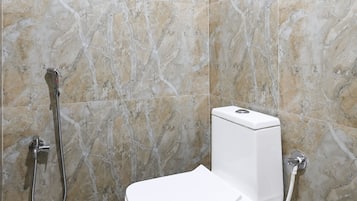 A bathroom with a toilet, a shower, and a hand dryer.