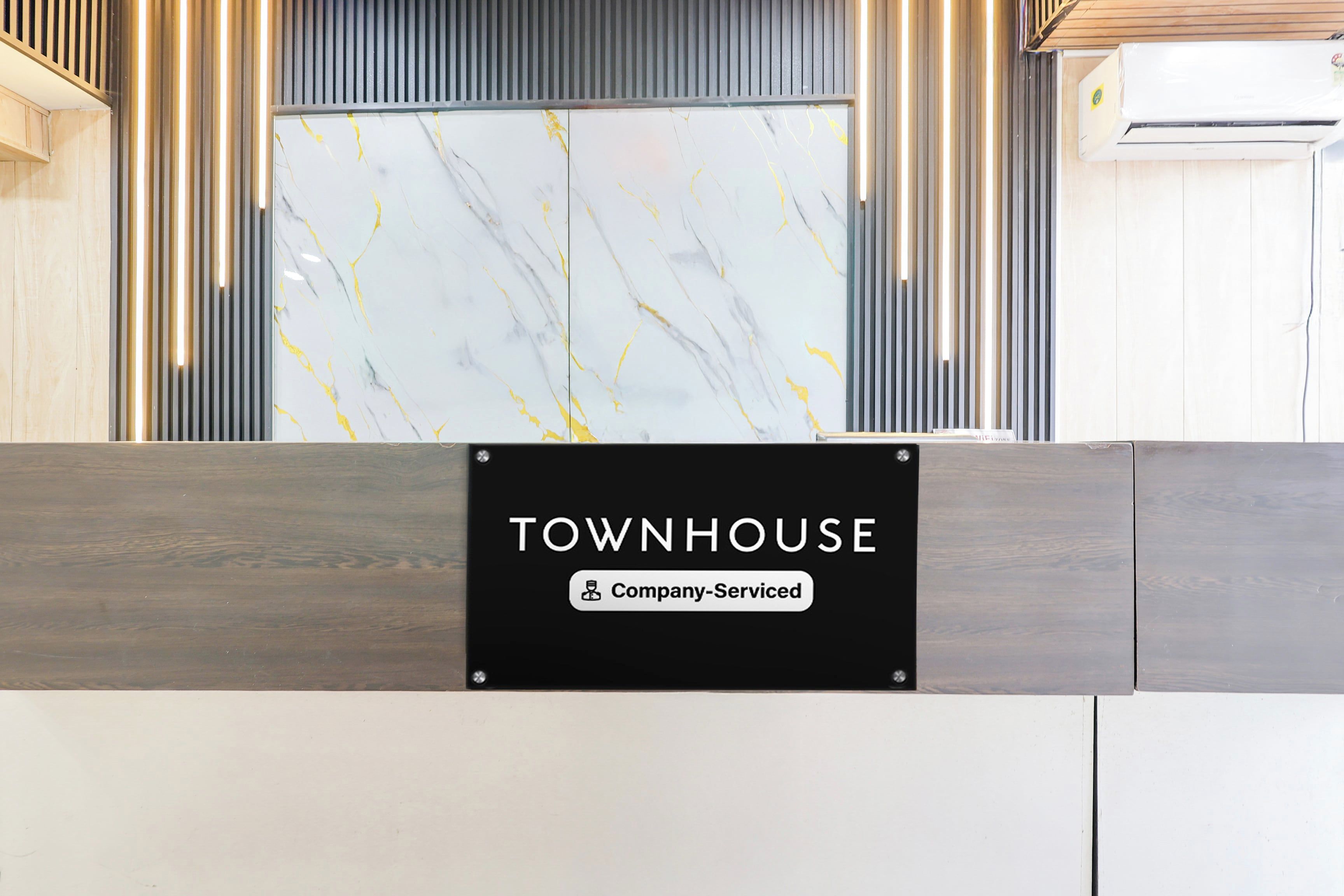 Een receptiebalie met een bord waarop 'TOWNHOUSE' en 'Company-Serviced' staat.