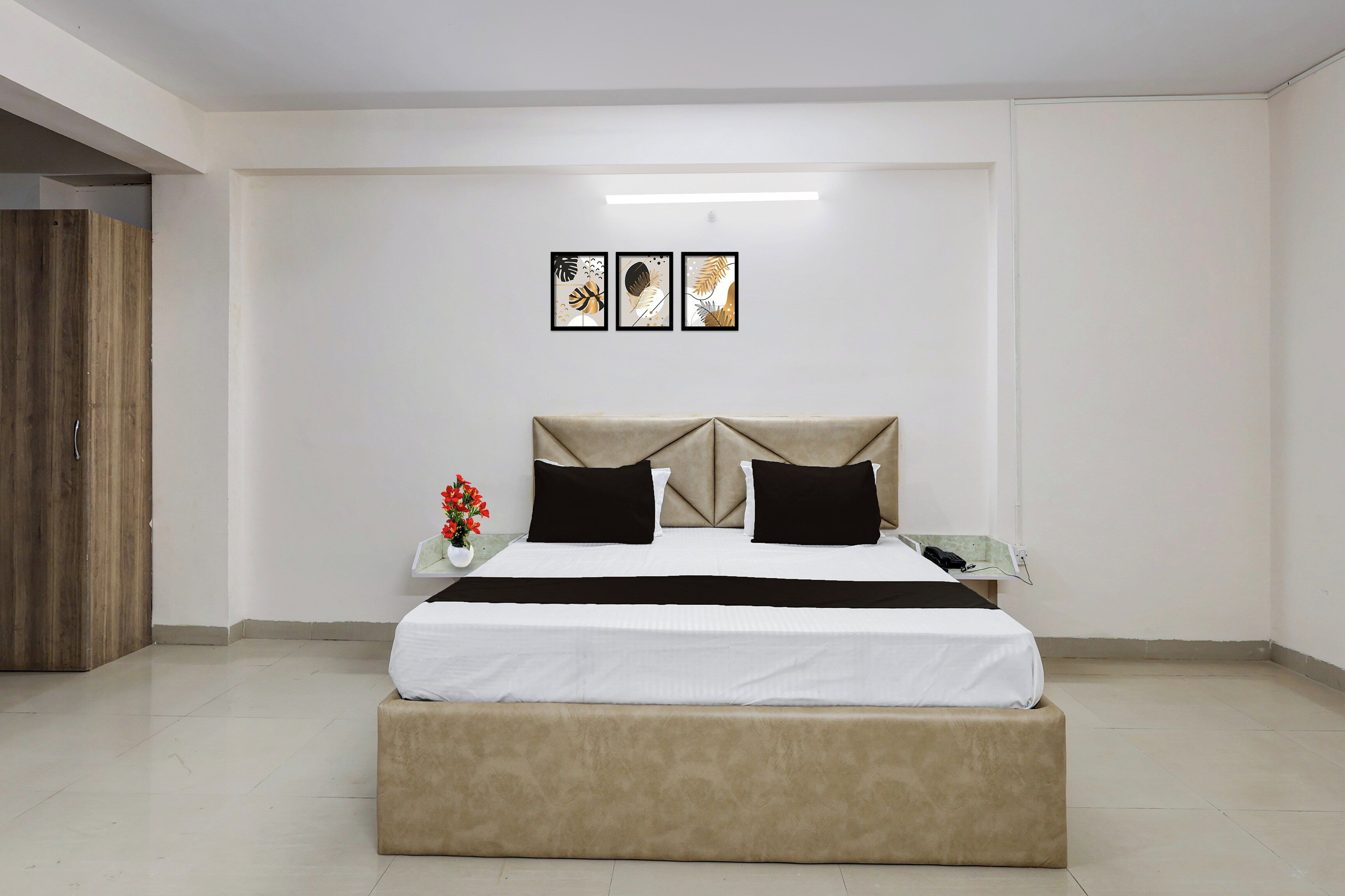 Een slaapkamer met een bed, nachtkastje en een bijzettafeltje met een telefoon.