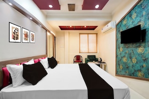 A hotel room with a bed, a flat-screen TV, a window with curtains, and a wall with framed artwork. - Townhouse Vijay Nagar Bus Terminal (Jabalpur)