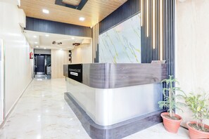 A reception desk with a 'OWNHOUSE' sign, a fire extinguisher, and potted plants. - Townhouse Vijay Nagar Bus Terminal (Jabalpur)