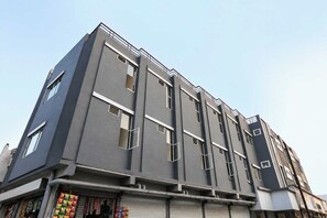 A multi-story building with a flat facade, large windows, and a visible commercial space at the ground level. - Townhouse Indore Airport Formerly (Indore)