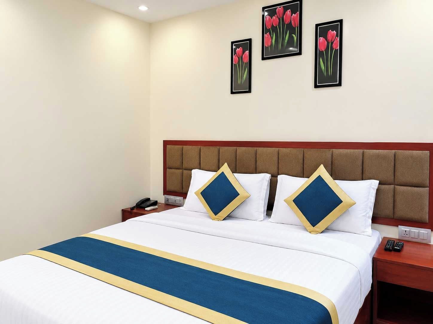 Een hotelkamer met een bed, een nachtkastje en een muur met drie ingelijste foto's.