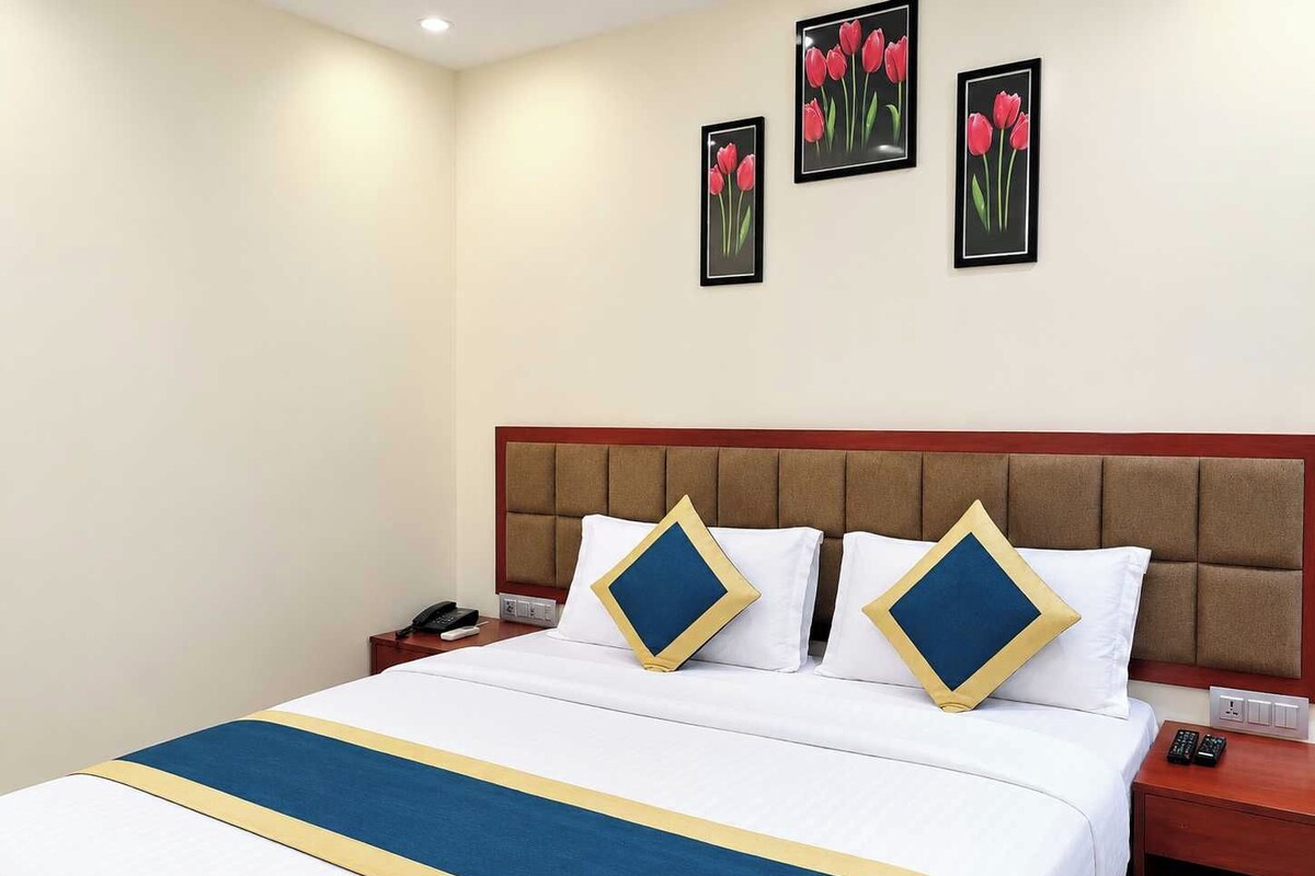 A hotel room with a bed, a nightstand, and a wall with three framed pictures.