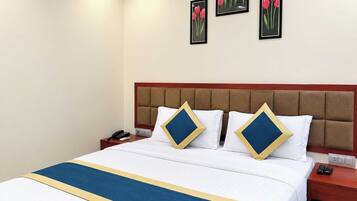 Een hotelkamer met een bed, een nachtkastje en een muur met drie ingelijste foto's.