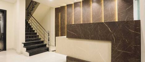 A modern interior with a staircase, marble wall, and recessed lighting.