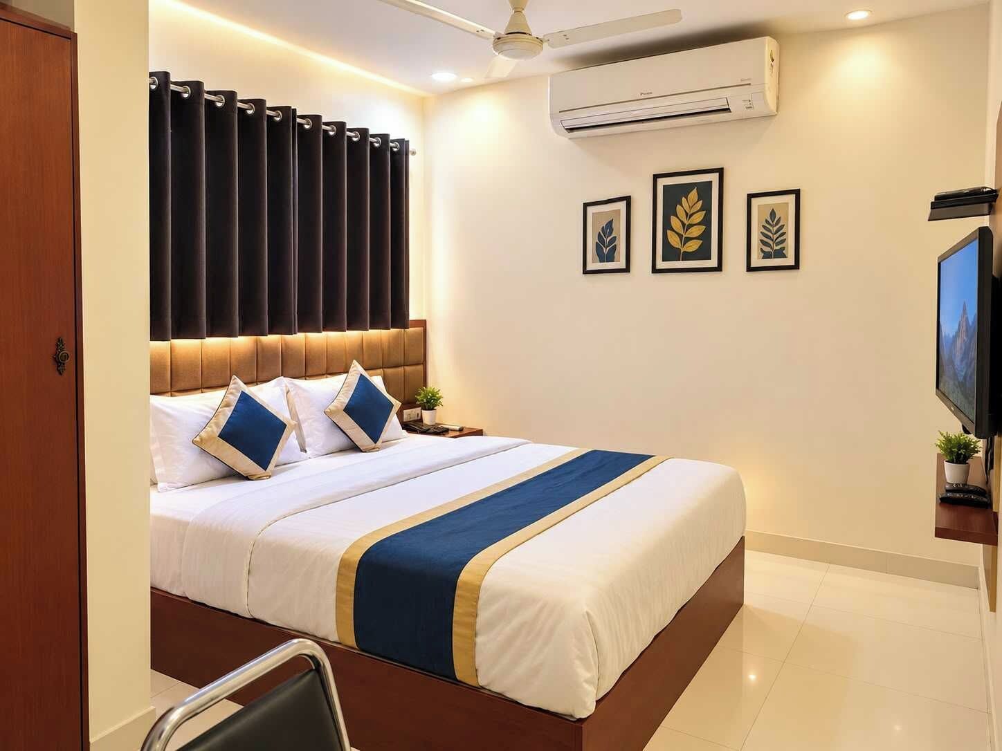 Habitación de hotel con cama, televisor, aire acondicionado y cuadros en la pared.