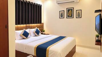 Habitación de hotel con cama, televisor, aire acondicionado y cuadros en la pared.