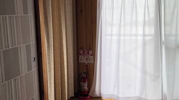 Ein Zimmer mit Holzboden, einer Schiebetür, einem Feuerlöscher und einem Vorhang.