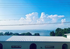 A view of a building with a metal roof and a clear sky with clouds.