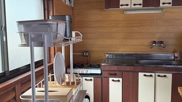 Une cuisine de taille réduite, avec des meubles de rangement en bois, un évier, une cuisinière et une petite fenêtre.