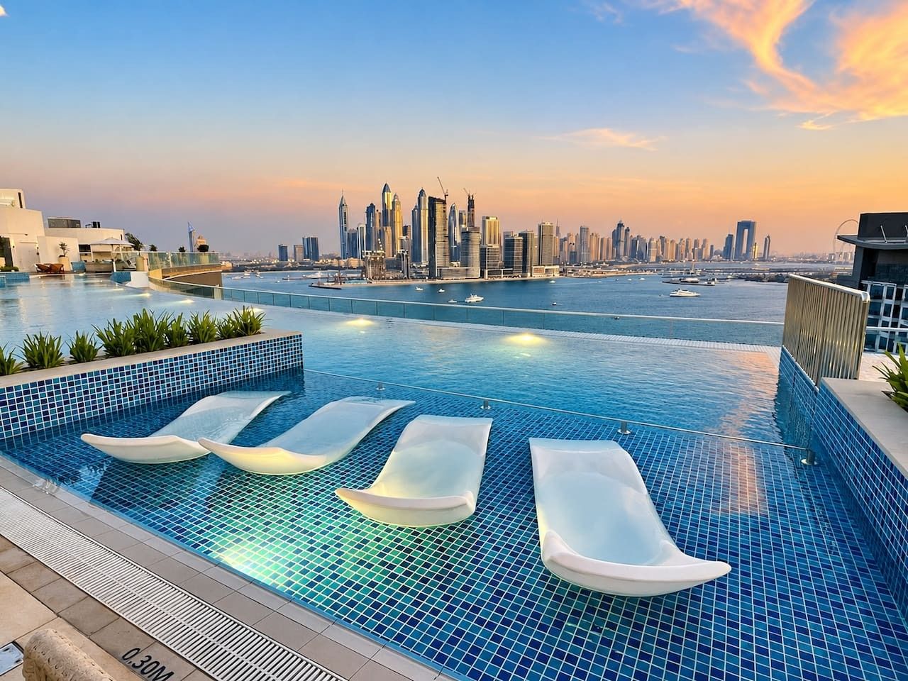 A rooftop infinity pool with lounge chairs and a city skyline view.