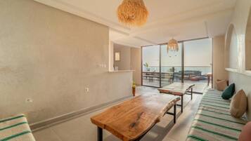 Una sala moderna con una mesa de madera, un sofá con cojines a rayas y un amplio ventanal con vistas al exterior.