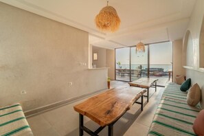 Una sala moderna con una mesa de madera, un sofá con cojines a rayas y un amplio ventanal con vistas al exterior.