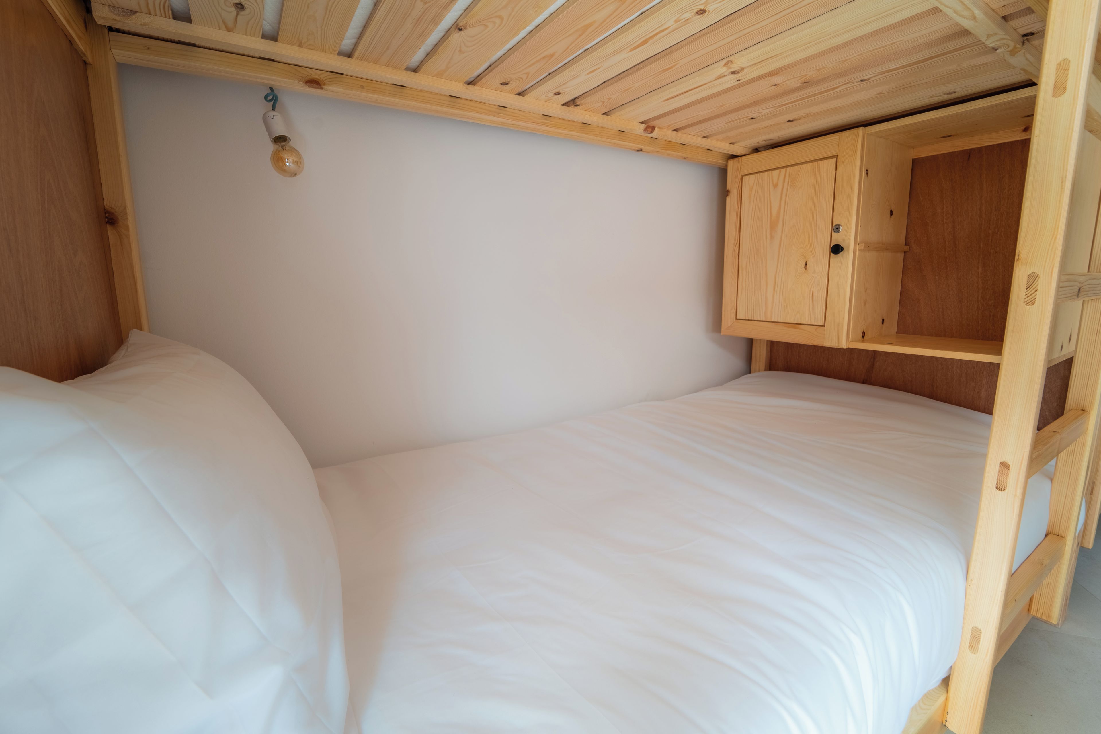 A small, wooden-framed room with a bunk bed and a wooden cabinet.