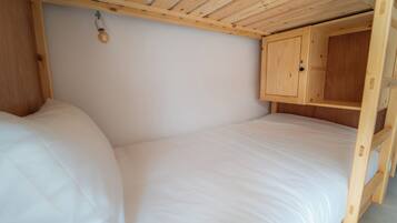 A small, wooden-framed room with a bunk bed and a wooden cabinet.