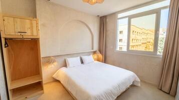 Un dormitorio con cama, un armario de madera, una ventana con vistas y una lámpara de techo.
