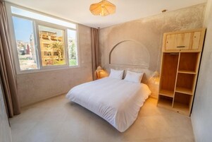 Un dormitorio con una cama, una ventana y un armario de madera.
