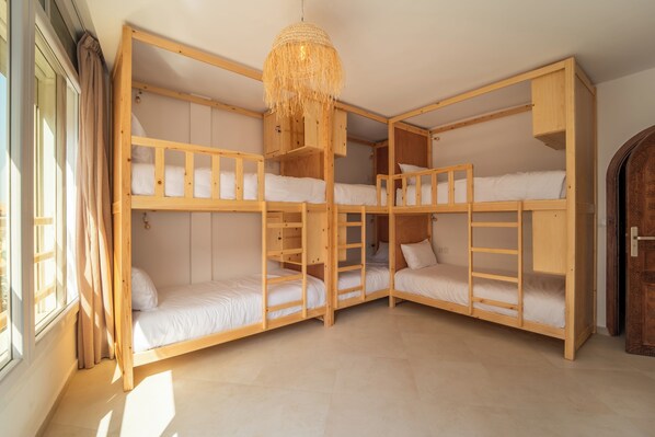 Habitación con literas de madera, una lámpara colgante y una puerta con diseños intrincados.