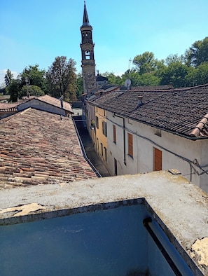 Une rue bordée de maisons aux toits couverts de tuiles en terre cuite, avec un clocher d’église et une ruelle étroite.