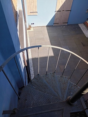A spiral staircase with metal railings leading to a wooden door.