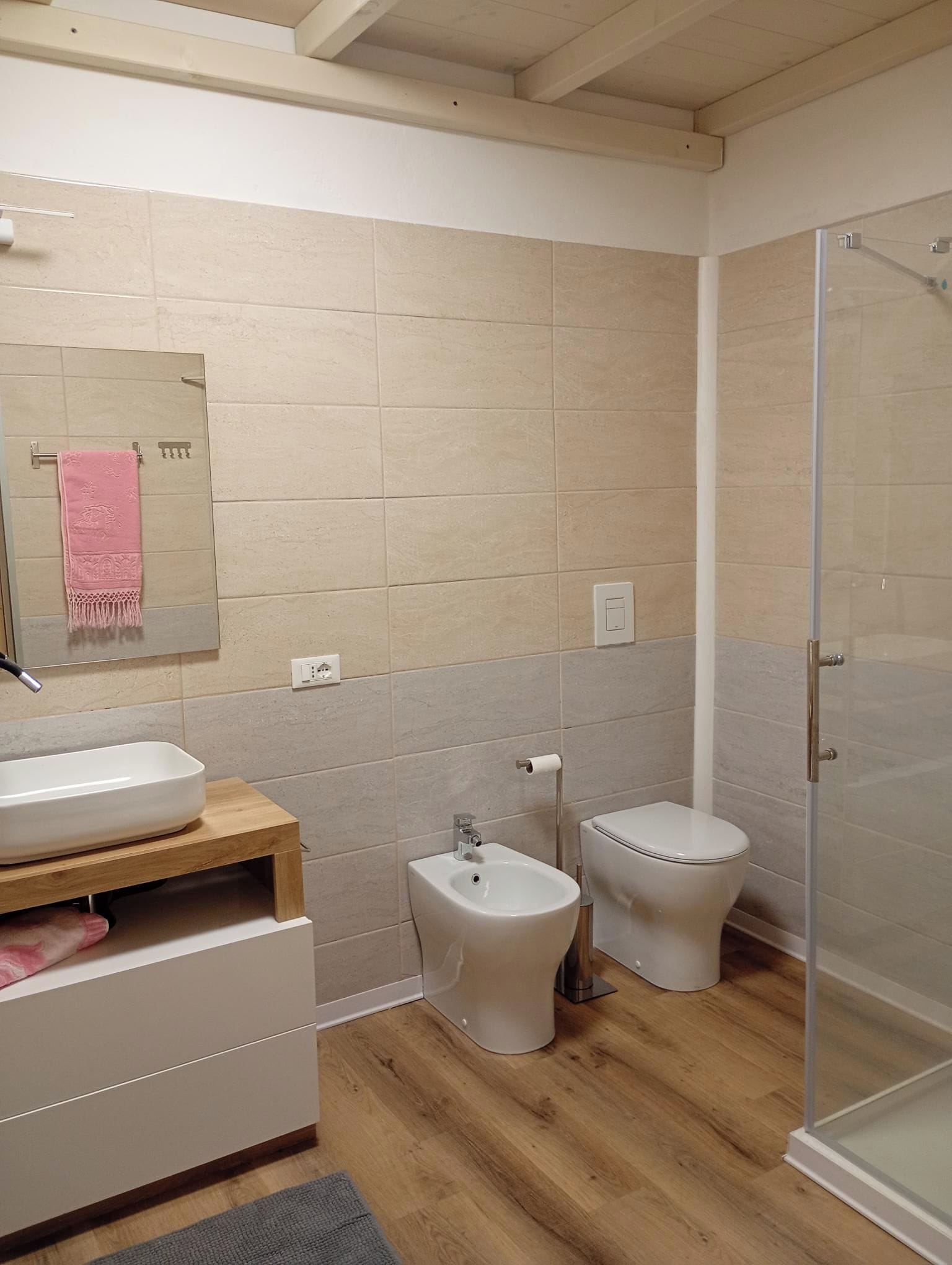 A modern bathroom with a sink, bidet, toilet, and a glass shower enclosure.