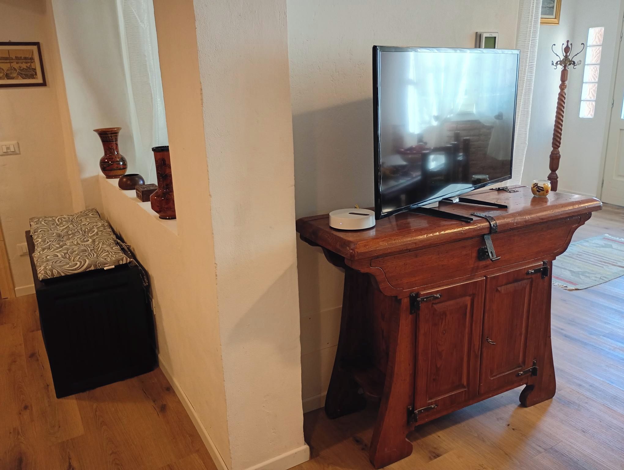 A wooden entertainment center with a flat-screen TV, a small table, and a decorative item.