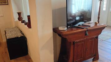 A wooden entertainment center with a flat-screen TV, a small table, and a decorative item.